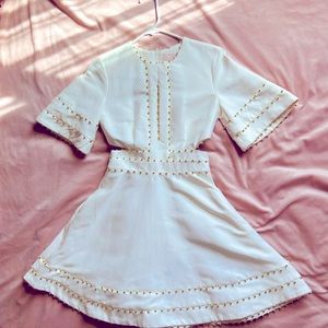 White fit and flare style party dress with waist cutouts and gold beaded details